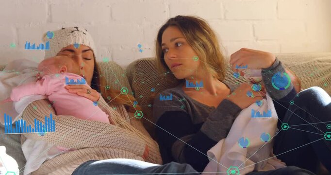 Cradling two infants, adults in chunky sweater and dark top on couch against white brick wall