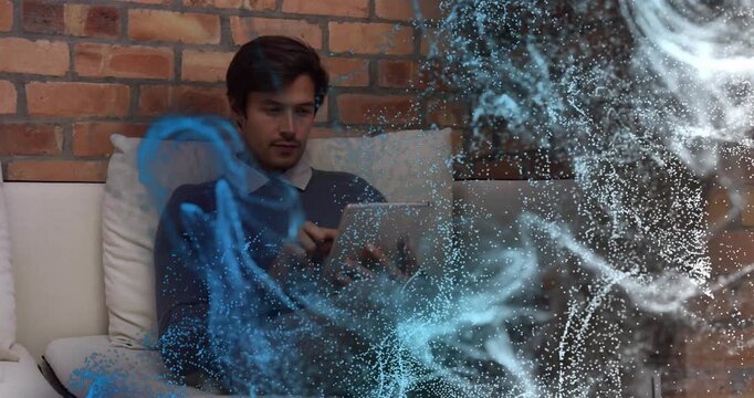 Man sitting on sofa picking tablet after particle reveal, second hand pointing, sharing tech