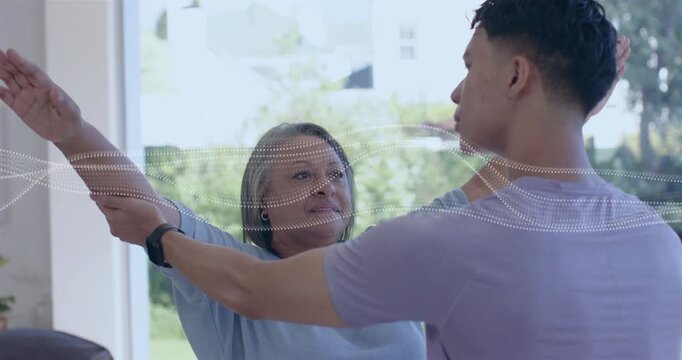 Caregiver placing hands on woman forearm, guiding arms up for therapy waveform crossing midline