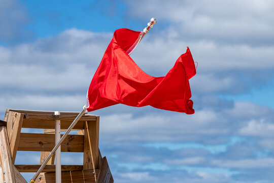 Red flag on a lifeguard chair waving in the wind with copy space 