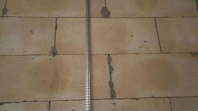 Static close-up shot of a metal plaster beacon installed on a wall of aerated concrete blocks. Preparation for plastering work during interior renovation or new construction.