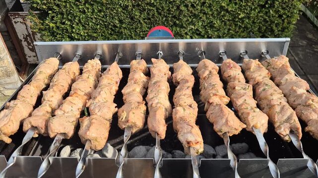 The kebabs are grilled on the coals while rotating.