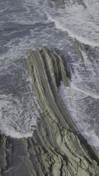 Flysch rock formations with ocean waves crashing
