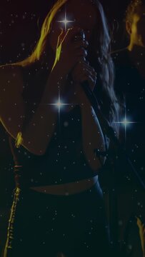 Vertical video: Woman singer singing, causing stars on mic and guitar, grading for cinematic music