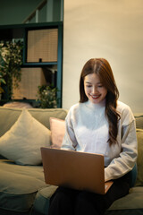 Woman working on laptop while sitting on sofa at home