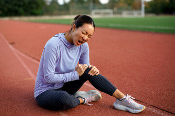 Naklejka premium Female athlete feeling knee pain after outdoor workout