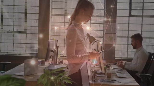 Woman walking office desks, checking smartphone after notification, sparkle overlay on monitors