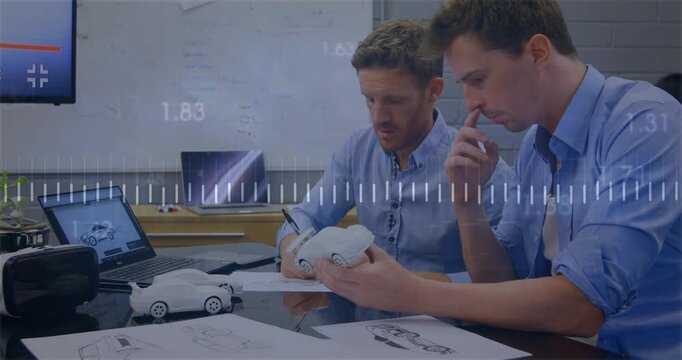 Two men doing auto review, right rotating prototype causing left noting sketches, waveform shifting