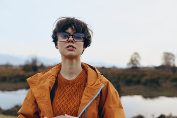 Young woman lifestyle outdoors wears orange jacket and sweater with glasses. Autumn nature...