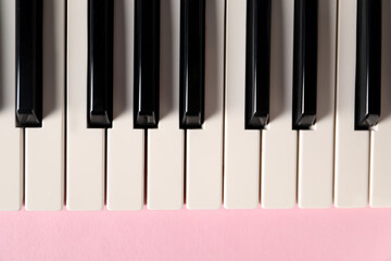 Naklejka premium Piano keys on pink background, top view. Musical instrument