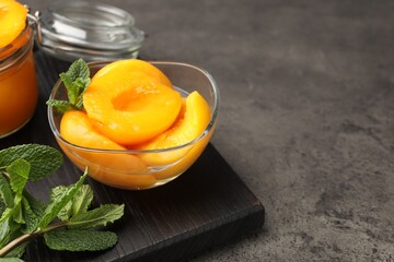 Pickled peaches and mint leaves on grey table, closeup. Space for text © New Africa