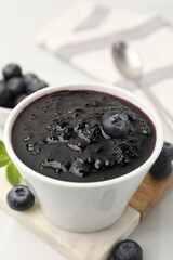 Sweet jam in bowl, blueberries and mint on white table, closeup