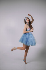 Naklejka premium Woman performs a dance in a blue dress with unique face paint in a studio setting during a photo shoot