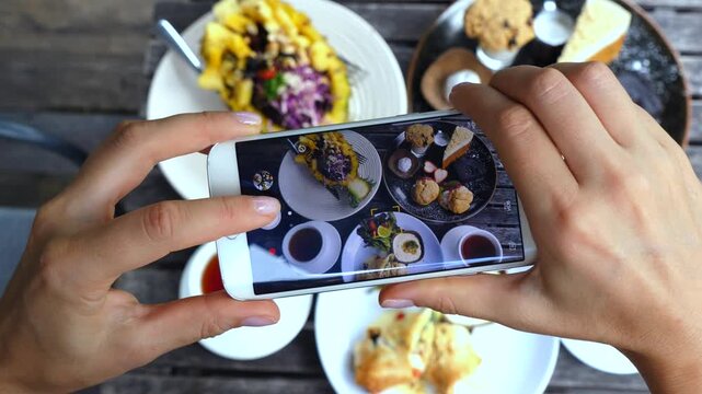 Top view of a food blogger's hands taking a photo of a healthy and delicious meal with a modern smartphone, capturing the vibrant colors and textures for social media content
