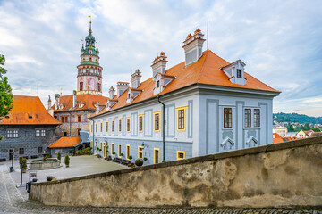 Obraz premium Visitors explore the grounds of Cesky Krumlov Castle in summer. The castle features historic architecture and offers views of the surrounding area. People enjoy walking and taking photos.