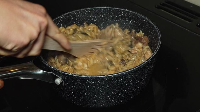 Close-up clip of cooking orzo, chicken and mushrooms in a saucepan