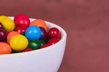 Colorful candy assortment in white bowl with space