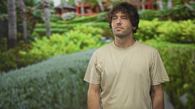 Man pointing finger to the distance showing a bare forearm while standing on a building garden pathway with closed eyes; contemplation decision.