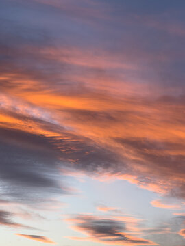 Vertical view of a dramatic sunset sky with vibrant orange, pink, and blue clouds