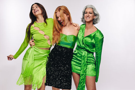 Three women laughing and hugging in studio