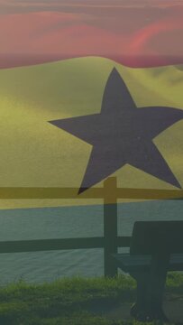 Vertical video: Sunset breeze drifting thin dark-star flag across cliff, showing bench and rail