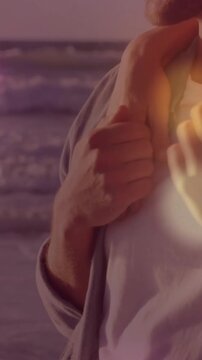 Vertical video: Man turning and smiling on sunset sea as woman reaching, clasping chest for travel