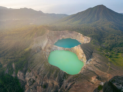 Aerial view of two lakes scenery on a clear sunny day in Kelimutu Lake in Indonesia with a mountain and evergreen trees. Top-down view captured with drone. Beautiful nature of the Flores countryside