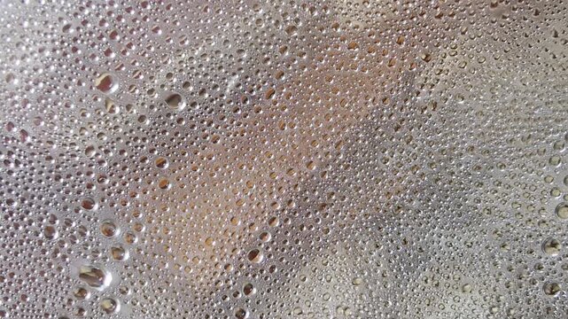 Condensation water drops on glass, moisture and humidity forming, evaporating, and collecting on a transparent surface, creating a stunning abstract background