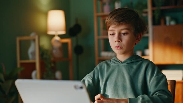 Schoolboy greeting tablet web camera starting video call sitting home closeup.