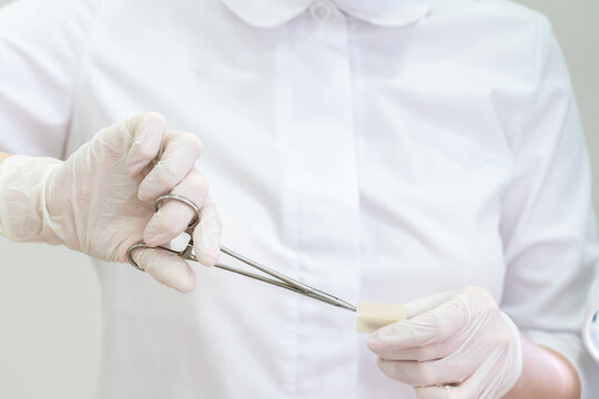 Doctor wearing gloves using a surgical forceps to open band aid