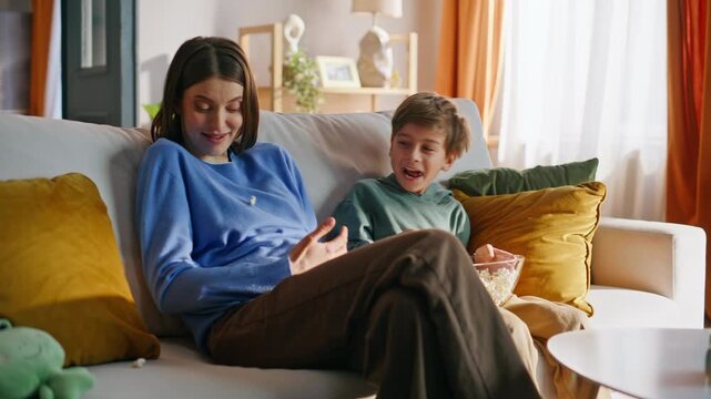 Happy mom son home leisure. Playful boy throwing popcorn playing fooling around