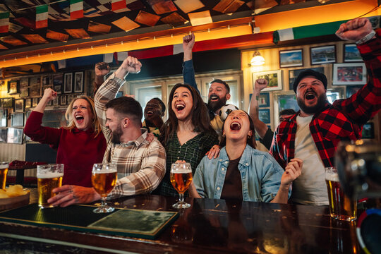 Diverse friends cheering watching soccer game in a pub