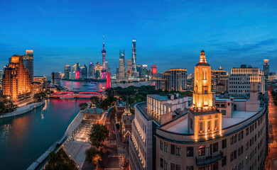 Naklejka premium A stunning blue hour view of the Shanghai skyline, featuring the iconic Lujiazui towers and Suzhou River, with illuminated bridges and historical architecture. Perfect for cityscape and urban photogra
