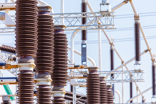Close up view of various elements and high-voltage insulators of a transformer substation, without people, at daytime on background of blue sky