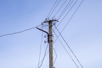 An electric pole supports multiple wires against a clear blue sky during daylight hours, showcasing utility infrastructure