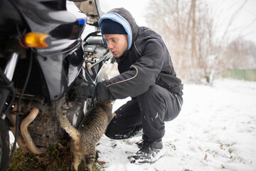 A man maintains a motorcycle in winter, motorcycle repair and maintenance