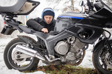 A man maintains a motorcycle in winter, motorcycle repair and maintenance