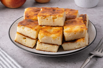 Freshly baked apple squares on a plate with apples in a bowl at a kitchen table during a daytime gathering