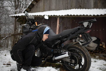 A man maintains a motorcycle in winter, motorcycle repair and maintenance
