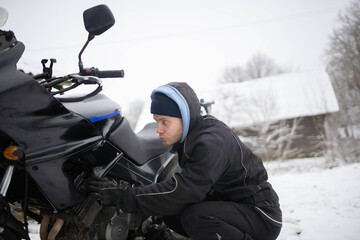 A man maintains a motorcycle in winter, motorcycle repair and maintenance