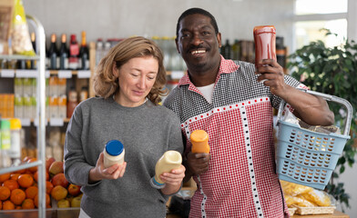Fototapeta premium Cheerful couple buying various sauces and mayonnaise in grocery supermarket