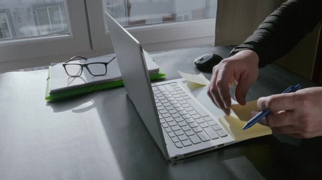 Male entrepreneur writing on sticky notes near a laptop