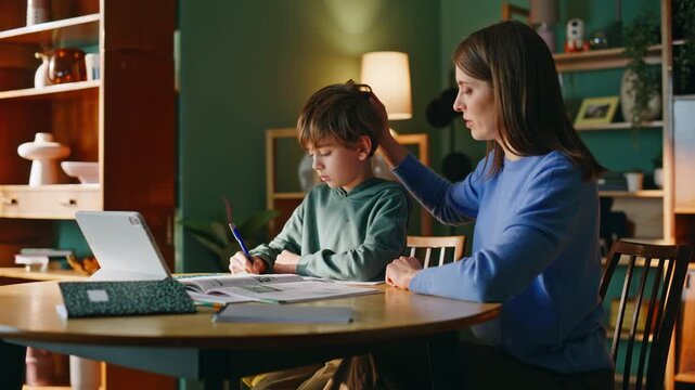 Mother praising son study browsing tablet online lesson sitting home closeup.