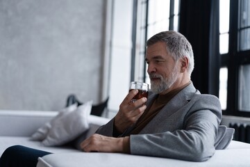Confident mature businessman chilling relaxing drinking enjoying whiskey after work.