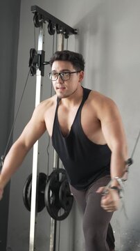 Muscular man performing cable chest fly exercise in gym using weight machine for bodybuilding training