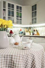 Fototapeta premium A table set for breakfast with tea and a bouquet of daffodils