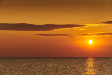 Fototapeta premium Golden Sunset Over Calm Ocean Horizon with Reflective Water