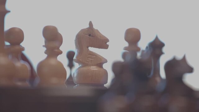 Two focused players are engaged in an intense game of chess. The camera captures a detailed close-up of a hand strategically moving a pawn across the wooden board.
