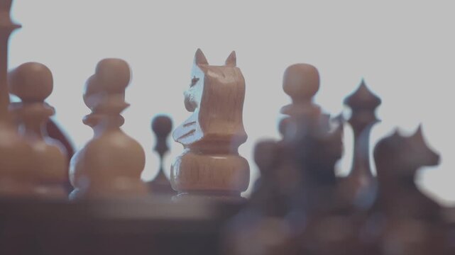 Two focused players are engaged in an intense game of chess. The camera captures a detailed close-up of a hand strategically moving a pawn across the wooden board.
