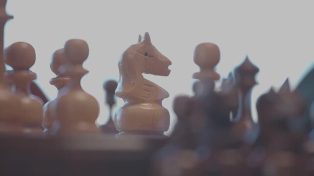 Two focused players are engaged in an intense game of chess. The camera captures a detailed close-up of a hand strategically moving a pawn across the wooden board.